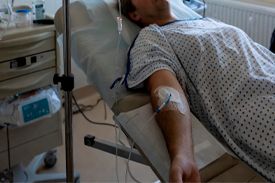 Пациент лежит на больничной койке с подключённой капельницей